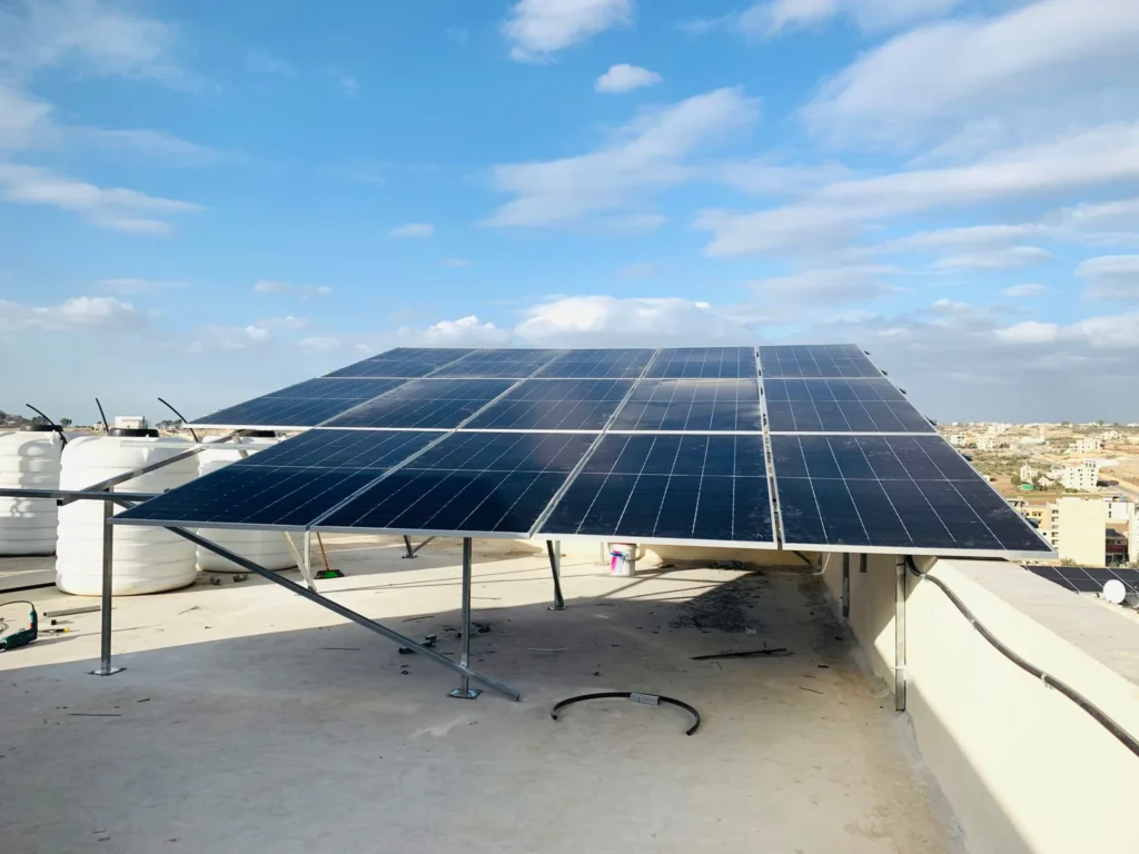 Solar panels installed on a rooftop with an urban landscape in the background on a sunny day.
