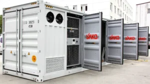 Several containerized SAKO energy storage systems with open doors, displaying the brand logo, in a factory yard setting.