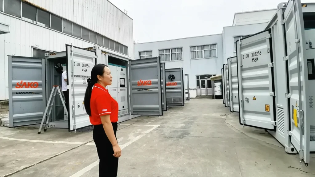 SAKO branded energy storage units with open doors and an employee in a red SAKO shirt in the Tedepe factory yard.