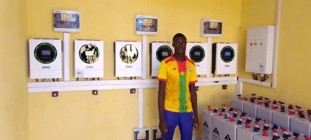 SAKO branded solar inverters mounted on a yellow wall with a series of energy storage batteries on the side, demonstrating renewable energy solutions.