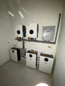 SAKO branded solar inverters mounted on a wall above three energy storage lithium batteries in a clean room setting.